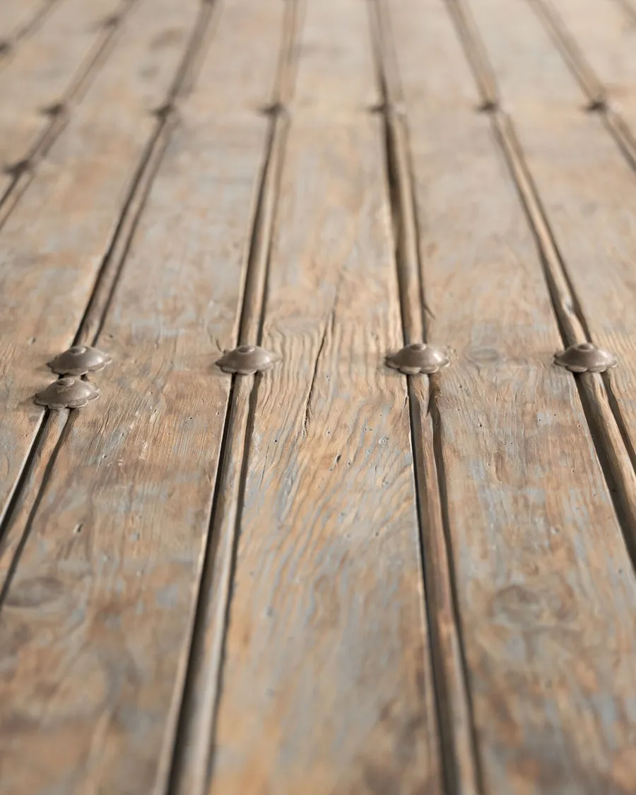 Detalle del tablero: tablas con pátina azulada y tachuelas de hierro