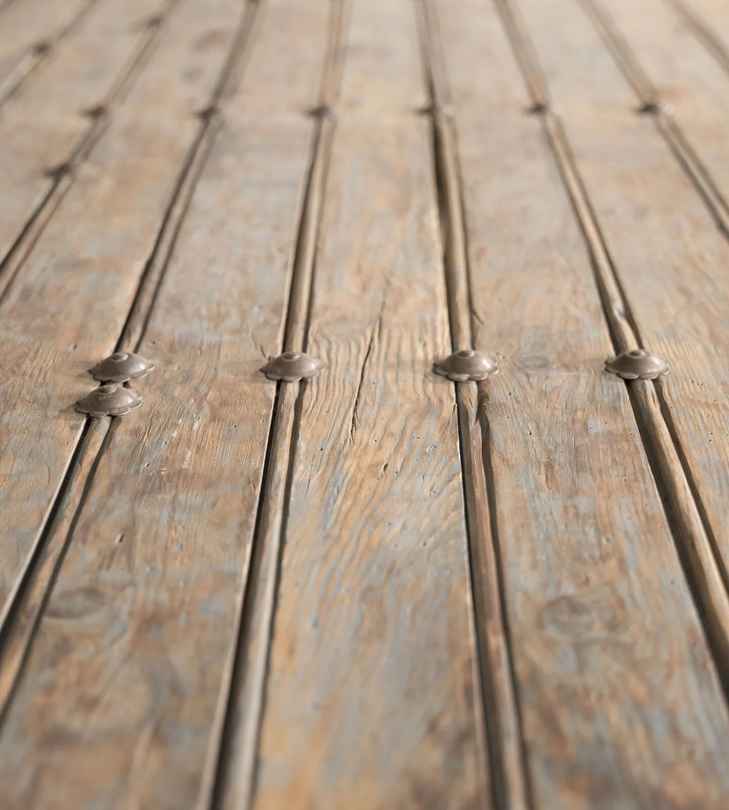 Detalle del tablero: tablas con pátina azulada y tachuelas de hierro
