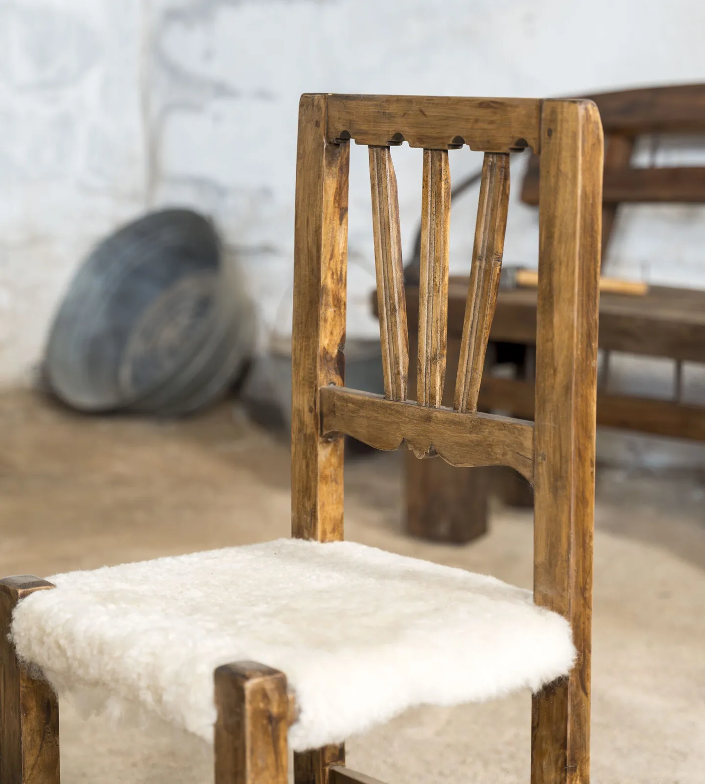 Silla de madera tallada con asiento de piel de oveja blanca