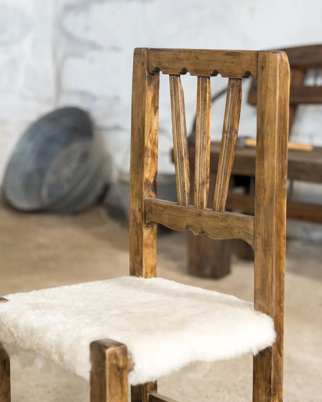 Silla de madera tallada con asiento de piel de oveja blanca