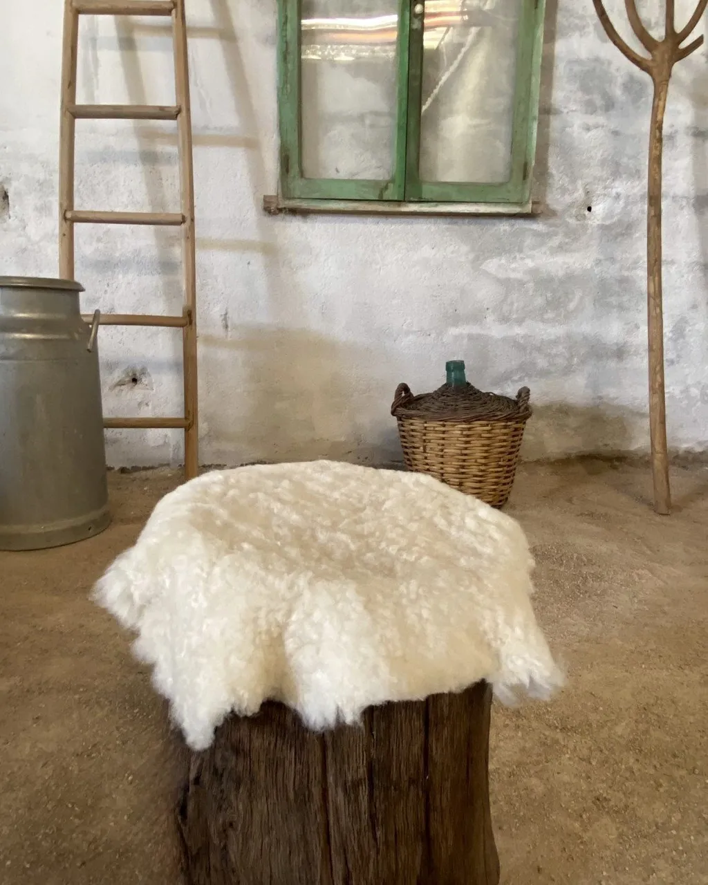 Taburete de tronco oscuro con piel de oveja encima, en el taller