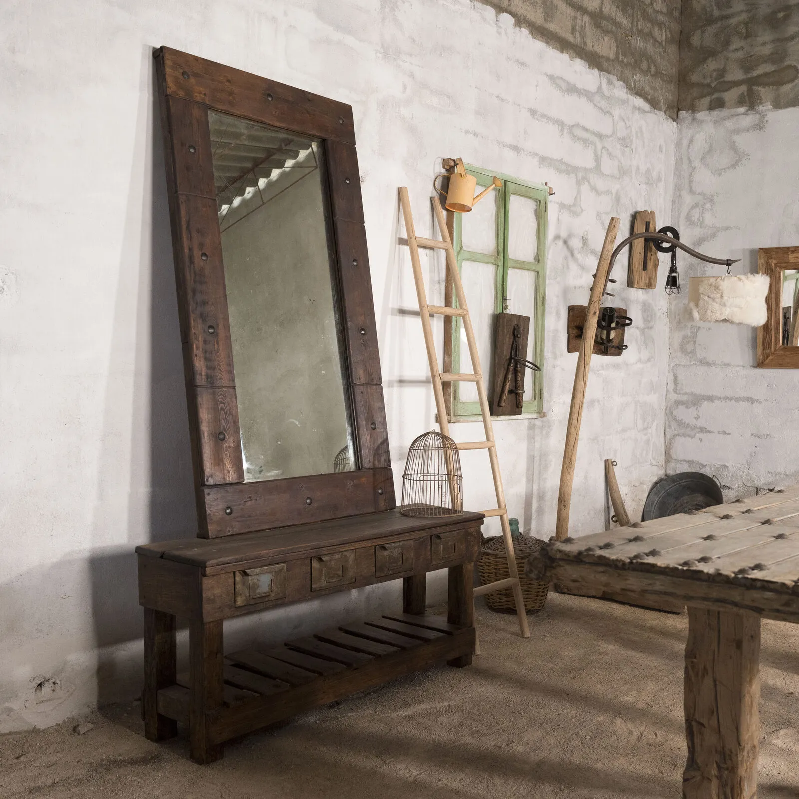 Tocador de madera oscura con espejo claveteado, junto a una escalera y una ventana verde